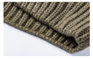 Close-up of thick cable knit texture and ribbed cuffs on dark olive green cardigan