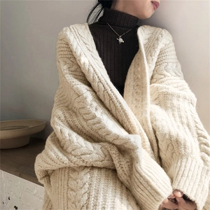 Close-up of off-white cable knit cardigan texture and thick wool stitch details