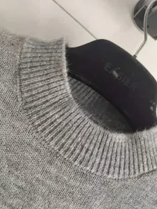 Gros plan détaillé du pull en tricot gris foncé à col rond avec texture en laine douce