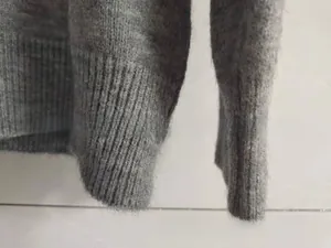 Gros plan détaillé du tissu gris du pull en maille montrant la texture des poignets