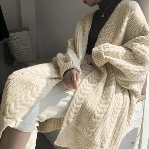 Detailed close-up of beige chunky cable knit texture on a loose oversized cardigan