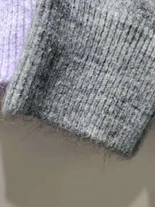 Gros plan sur la texture tricotée grise et violette d'un pull doux à manches longues