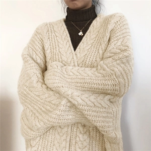 Close-up of cream cable knit texture on oversized long cardigan sweater for winter