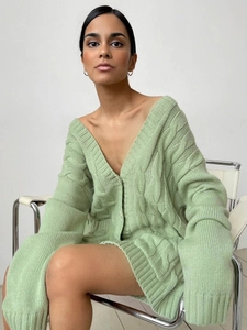 Detail of light green cable knit cardigan with V-neck and oversized loose fit