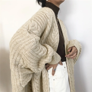 Close-up of beige cable knit cardigan with chunky texture and loose drop-shoulder design