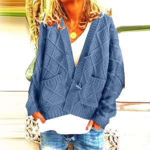 Close-up of blue cable knit cardigan featuring horn buttons and classic V-neckline detail