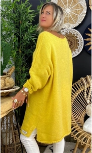 Detailed knit texture of a bright yellow oversized sweater featuring a side slit design