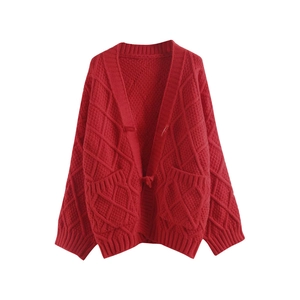 Close-up of bright red cable knit cardigan showing detailed texture and ribbed hem