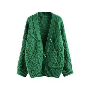 Detail of dark green cable knit cardigan featuring diamond textures and front pockets