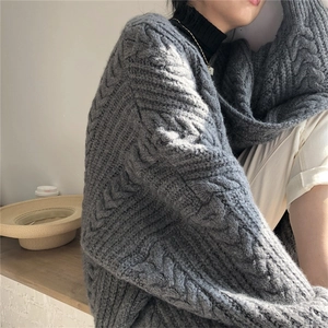 Detail of grey cable knit cardigan showing thick texture and intricate patterns