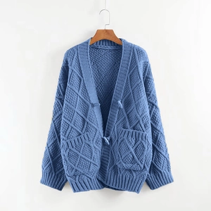 Detail of light blue cable knit cardigan with V-neck and symmetrical front pockets