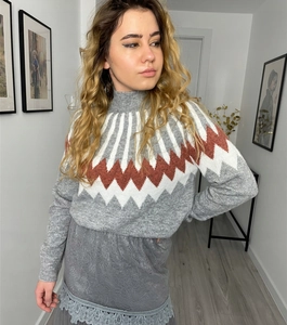 Close-up of diamond pattern knit sweater and delicate lace hem on matching grey skirt