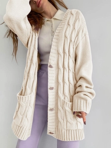 Detail of loose-fit knit cardigan in creamy white featuring classic cable-knit texture