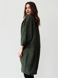 Detailed close-up of dark green waffle knit texture on a long oversized cardigan sweater