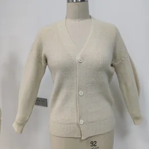 Close-up of cream knit cardigan featuring vertical rib texture and white buttons