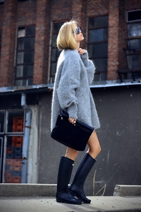 Détail d'un pull oversize en mohair gris porté avec des bottes de pluie hautes noires