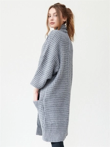 Long grey knit cardigan with V-neck and diamond pattern shown on model in studio