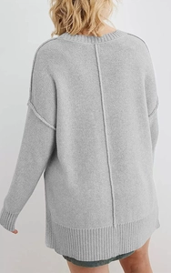 Detailansicht grauer Oversize-Strickpullover mit vertikaler Rückennaht und weicher Textur
