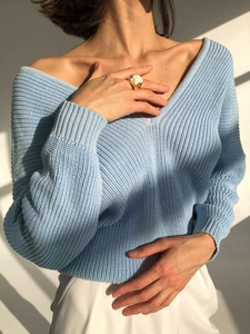 Detail of light blue loose knit sweater with V-neckline and ribbed texture in sunlight