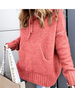 Detail of coral pink knit hoodie featuring a kangaroo pocket and drawstring hood