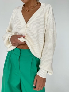 Close-up of beige knit cardigan featuring V-neckline and large buttons texture details