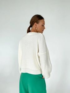 Detailed texture of white vertical knit cardigan sweater with ribbed cuffs and hemline
