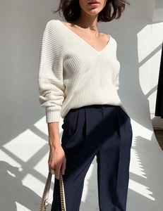 Detailed view of white V-neck knit sweater with thick ribbed texture and drop shoulder