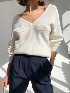 Close-up of white rib-knit V-neck sweater fabric showing soft vertical textures