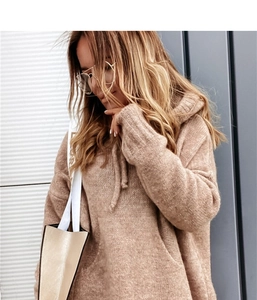 Detail of camel knitted hoodie featuring a drawstring hood and large kangaroo pocket