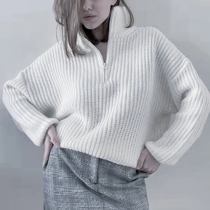 Detail of white knit sweater showing half-zip high neck and ribbed texture