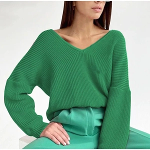 Detail of green V-neck knit sweater showing ribbed texture and drop shoulder design