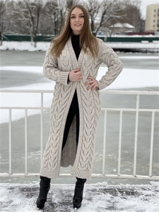 Close-up of thick cable-knit texture on a long beige winter cardigan in snow