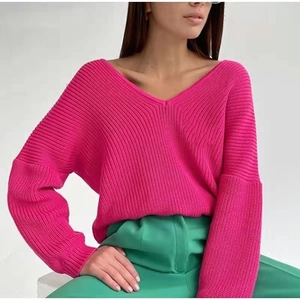 Detail view of pink ribbed knit texture on a loose off-shoulder V-neck sweater