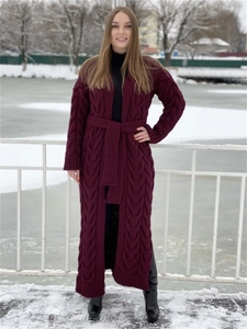 Deep burgundy long cable knit cardigan sweater featuring a waist belt in a snowy setting