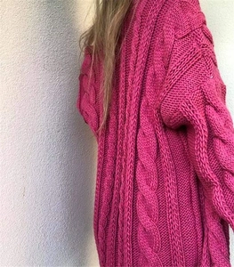 Close-up of chunky cable knit texture on a rose red loose-fit cardigan sweater