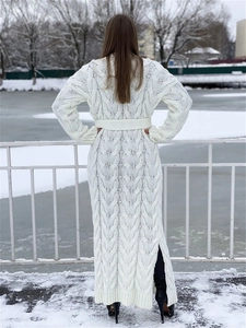 Close-up of white cable-knit texture and side slit detail on long knit cardigan