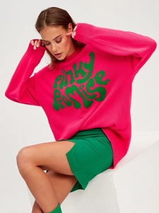 Detail view of pink knitted sweater with green Pinky Promise lettering and green skirt