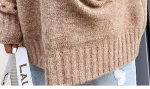 Detailed close-up of brown chunky knit sweater texture and wide ribbed hem finish
