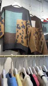Detail of loose knit sweater featuring color-block design and leopard print pattern