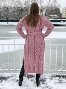 Detail of pink cable-knit long cardigan featuring thick texture and side slit in snow