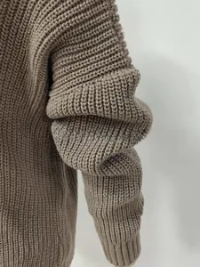 Close-up of thick knit texture on brown long-sleeved sweater showing weaving details