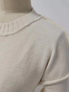 Detailansicht des cremefarbenen Strickpullovers mit Rundhalsausschnitt und Rollnahtschultern