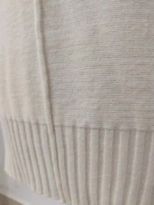 Detailaufnahme des cremeweißen Strickpullovers mit vertikalem Rippsaum und Textur