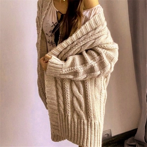 Macro detail of beige oversized cable knit cardigan showing thick textured wool stitches
