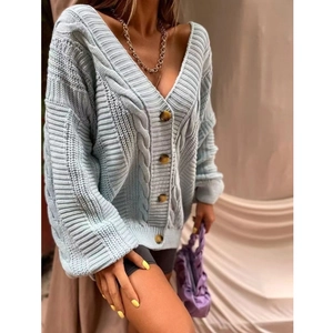 Gros plan sur un cardigan bleu clair en maille torsadée avec des boutons en écaille de tortue