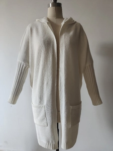 Detail of white hooded knit cardigan featuring large patch pockets and ribbed sleeve texture