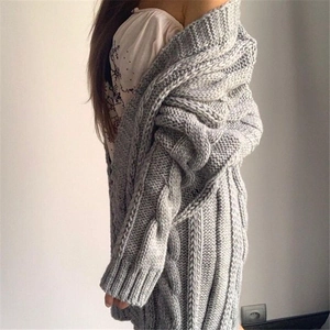 Detail of grey cable-knit texture and loose ribbed cuffs on the long cardigan sweater