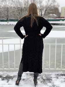 Detail of black cable-knit long cardigan featuring side slits and a matching waist belt