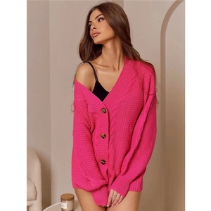 Détail de la maille torsadée rose fuchsia et des grands boutons foncés du cardigan