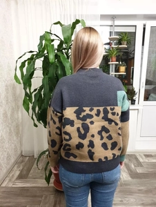 Detail of loose-fit knit sweater with leopard pattern back and colorful patchwork sleeves
